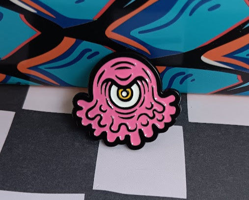 Pink and black octopus-shaped enamel pin on a checkered background