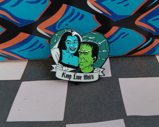 Pin with a design of a couple and 'Keep Love Weird' text on a checkered surface.